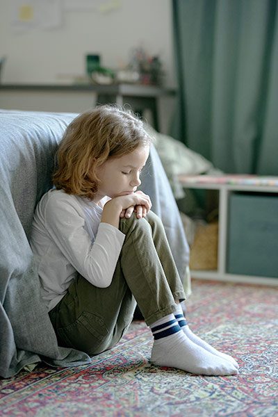 Niño triste sentado en el suelo experimentando sus miedos o depresiones.